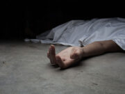 Police Investigate Headteacher’s Death in Akatsi Guest House. a hand extending from underneath a white sheet covering a body on the floor.